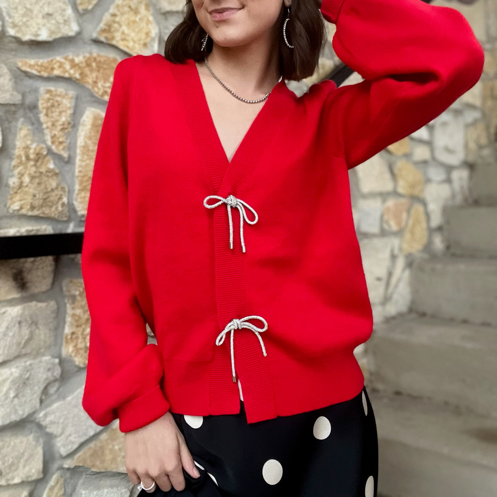 red bow cardigan, bow detail sweater, rhinestone bow cardigan, puff sleeve cardigan, girly red sweater, festive holiday cardigan, holiday party outfit top, game day red sweater, chic knit cardigan, feminine red cardigan, statement cardigan sweater, cozy yet polished cardigan, viscose knit cardigan, winter boutique cardigan, red knit sweater, playful feminine sweater, sophisticated red cardigan, trendy bow button cardigan