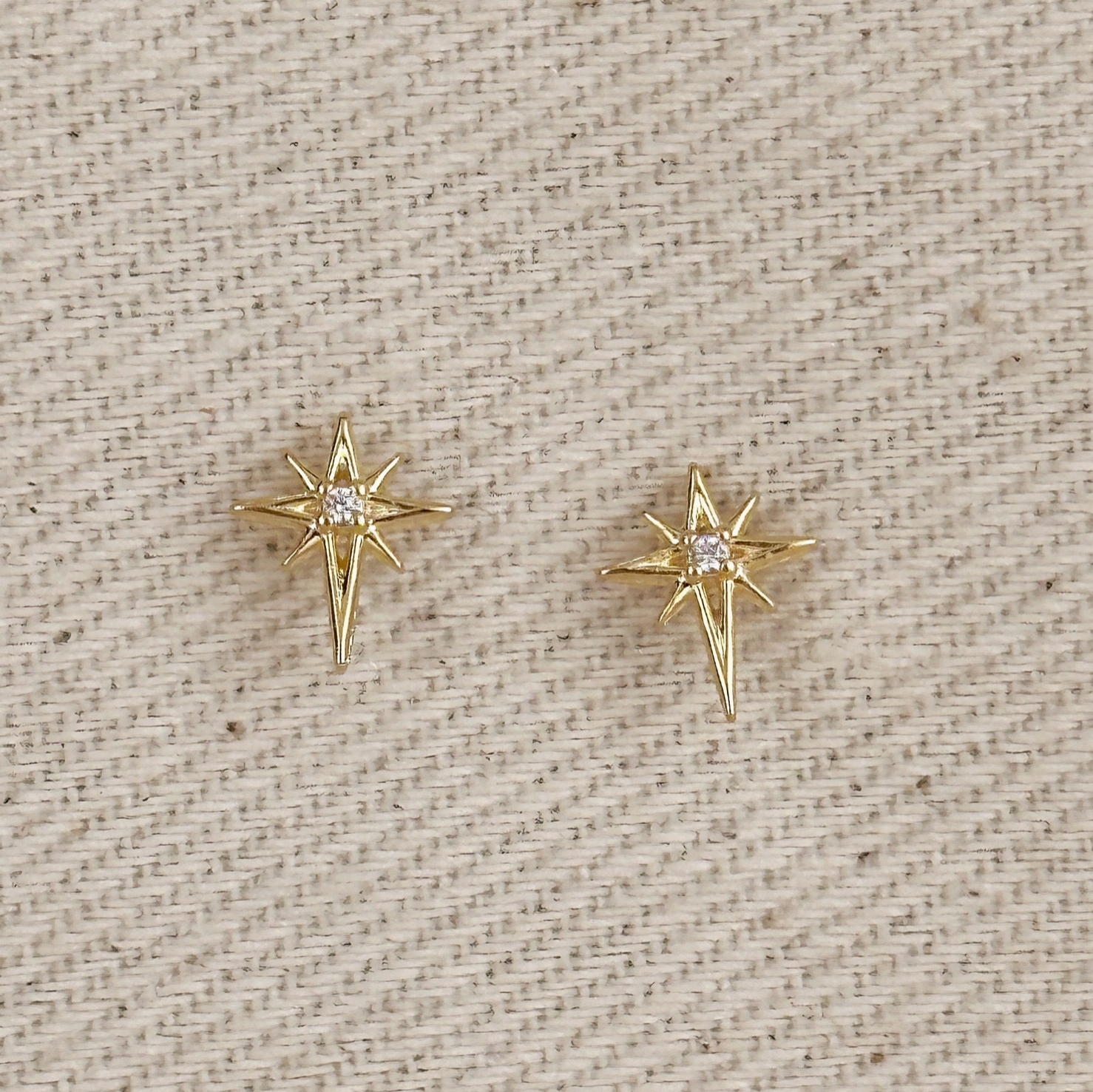 Gold star-shaped stud earrings with a central clear gemstone, gold starburst earrings featuring a sparkling center stone,Minimalist gold North Star studs with a clear crystal center, stud earrings, 18k gold earrings, water resistant earrings, karadise boutique star earrings, McKinneu Texas Star Earrings